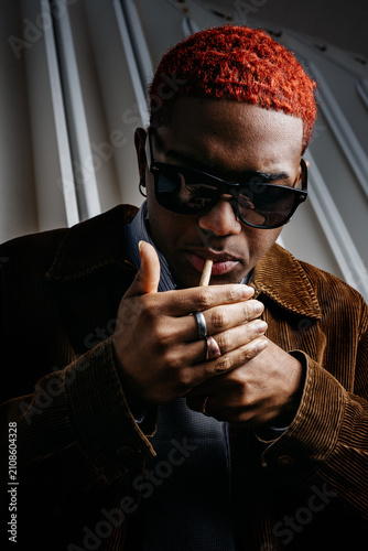 Close-up of a black man lighting a cigar with a tough look on his face