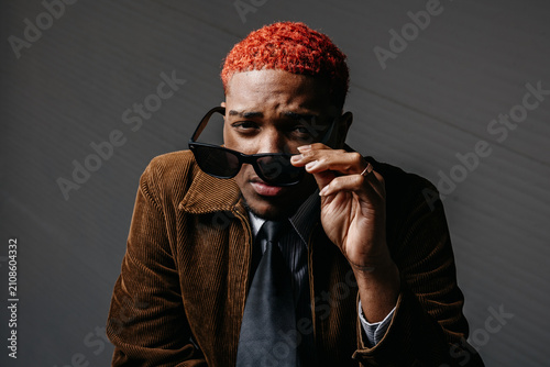 Принти на полотні A Black man looking at the camera with a sad expression as he takes off his sung