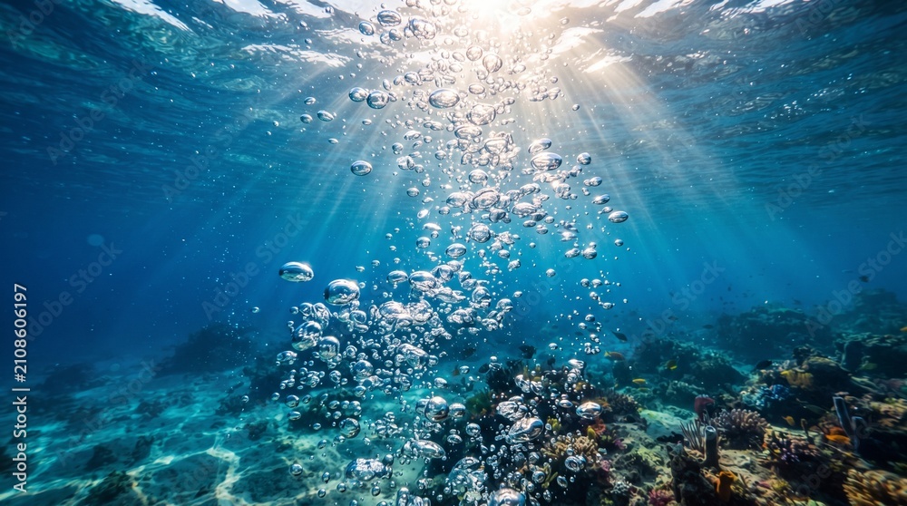 Naklejka premium Underwater bubbles rise toward the surface of the ocean where sunlight penetrates the clear blue water above a coral reef, creating a serene and natural marine environment with ample copy space area.