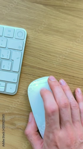 Finger clicking a mouse while scrolling forward and back. Vertical view of hand navigating with a trackpad gesture. Close-up moment of everyday computer control at a desk..
