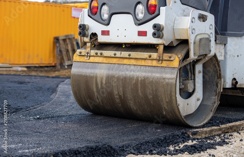 Obraz na plátne Construction worker uses a road roller to flatten asphalt on a new road at a con