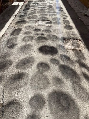 Amazing geometric shaped shadows formed by the crocheted lace doilies hanging over the street