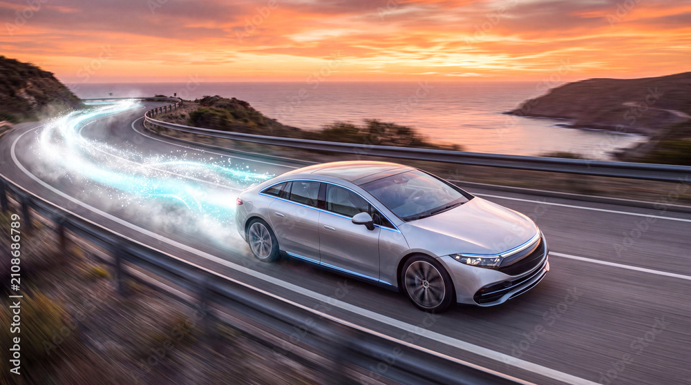 Naklejka premium Futuristic electric car driving on coastal road. Modern EV vehicle with motion light trails.