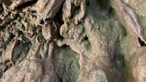 The camera slides over the bizarre formations of a rock cave covered in moss, from the ceiling of which water drips down. Concept mysterious cave, geological wonders, erosion power, spring water. High