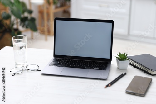 Comfortable workplace with laptop on white table indoors, closeup