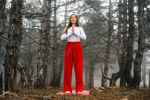 Brave woman standing on sadhu nail boards in a foggy forest