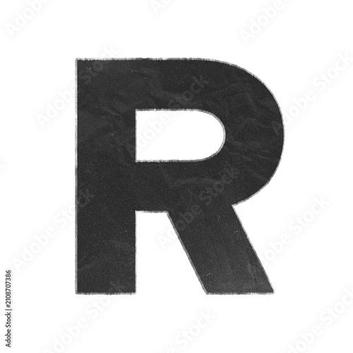 Uppercase letter R cutout from black textured paper with distressed white edges isolated on white background