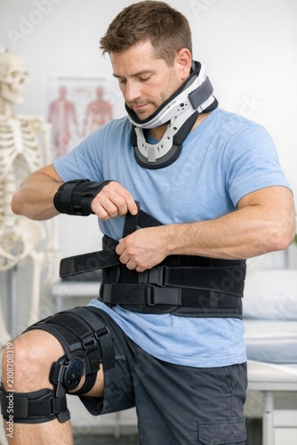 A man is shown wearing a blue shirt and an arm brace, likely indicating he has an injury or condition affecting his arm