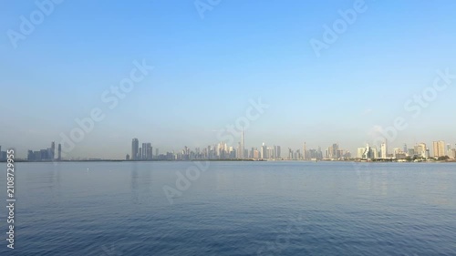 Morning panoramic skyline of Downtown Dubai with Burj Khalifa dominating modern architectural landscape beyond Dubai Creek under clear blue sky
