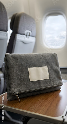 Grey clutch bag on airplane tray table. Stylish accessory for travel and business trips.