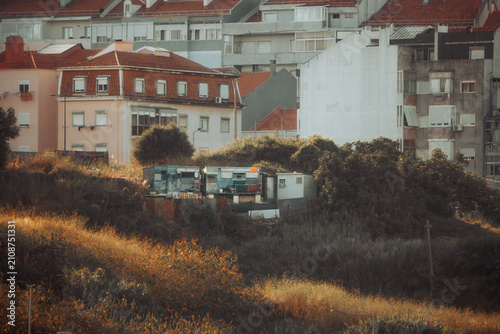 Foto Telephoto view of makeshift shelters clustered on an overgrown vacant lot beneat