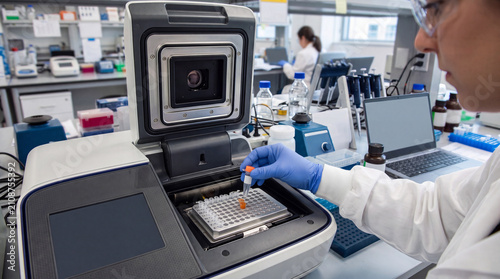 high-tech laboratory, molecular biology, PCR thermal cycler, green PCR rack, scientist loading samples, microtubes, cinematic bokeh, laboratory glassware, reagent bottles, biotechnology, DNA analysis