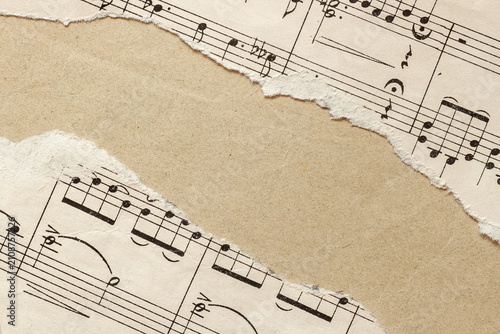 Sheet music paper fragment on kraft background, copy space. Torn pieces of vintage sheet music, textured kraft paper background. Musical collage, classical music, creativity, education themes