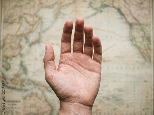 Human hand reaching over vintage world map with shallow depth of field for travel and logistics marketing