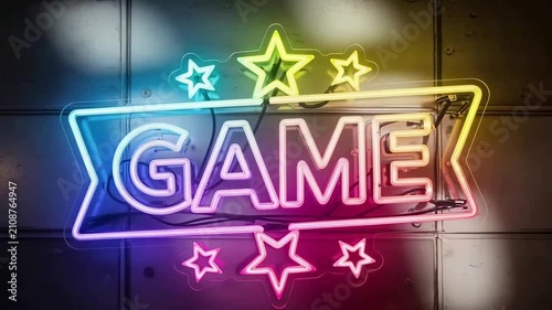 A vibrant, multicolored neon sign spelling out the word GAME, adorned with stars on a dark tiled wall.