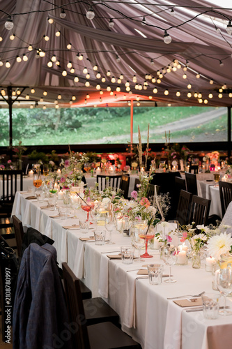 фотографія Elegant candlelit wedding reception with floral tablescape beneath glowing strin