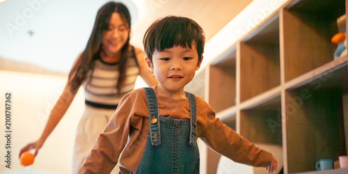 Little boy playing indoors with his mother, smiling in a happy moment