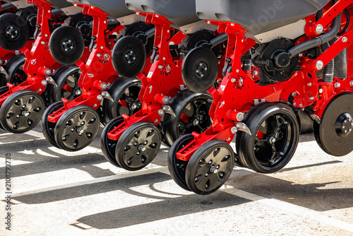 Agricultural seeding machinery planter press wheels close up. Modern precision farming grain seeder row units mechanism on red frame and industrial transport vehicle engineering details.