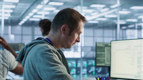 Smiling engineer inspecting server rows in data center while capturing firewall review, server bottlenecks and technical problem solving.