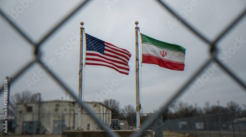 Foto The national flags of the United States and Iran flying side-by-side behind a chain-link fence, symbolizing geopolitical tension and international relations