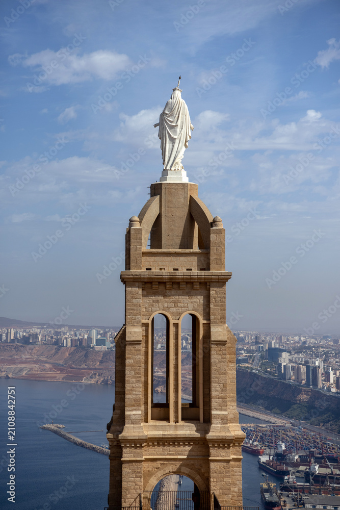 Fototapeta premium White Virgin Mary Statue Atop Santa Cruz Bell Tower with Oran Harbor Panorama