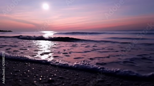 Serene Sunset Over a Pebble Beach with Gentle Waves and a Pink-Hued Sky