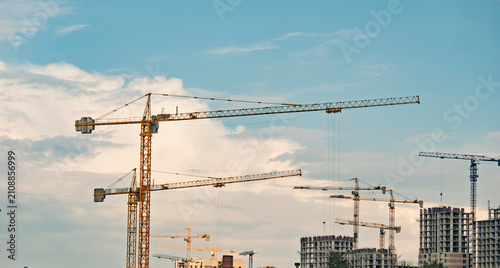 Tower Cranes at Construction Site Under Blue Cloudy Sky