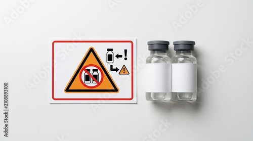 Overhead flat lay of two similarly shaped vials placed beside a look-alike sound-alike warning card