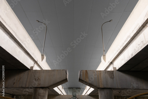 Canvastavla Symmetrical low angle view under a concrete highway overpass bridge with street
