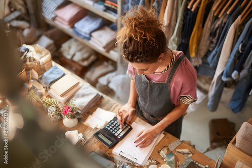 High angle portrait of female businesswoman counting finances using calculator in small shop, small business concept