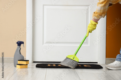 Woman sweeping doormat in h...