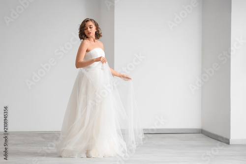 Beautiful bride wearing wedding dress in light room