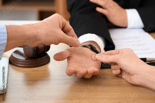 Принти на полотні Male divorce lawyer taking wedding rings from mature couple in office, closeup