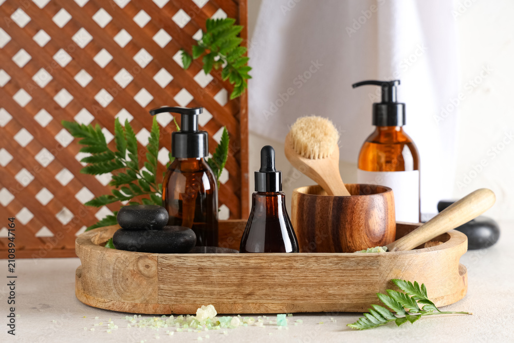 Fototapeta premium Wooden board with cosmetic products, spa accessories and fern leaves on light table