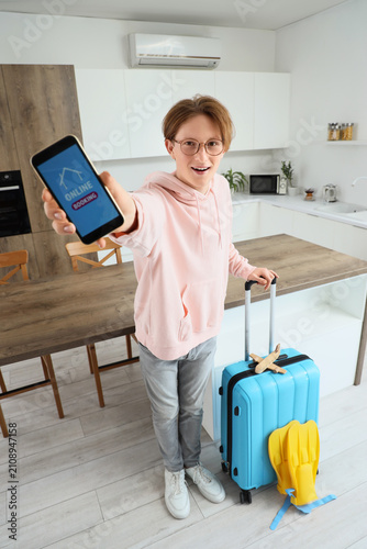 Canvastavla Male tourist with suitcase and mobile phone booking hotel room online in kitchen