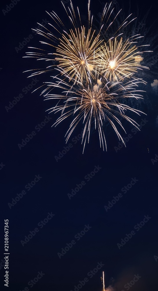 Fototapeta premium Sophisticated holiday celebration backdrop featuring brilliant golden and shimmering silver fireworks exploding across a deep navy blue sky, golden, year-end, bokeh