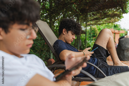 Obraz na płótnie Teen boys using cell phones outdoors relaxing social networking