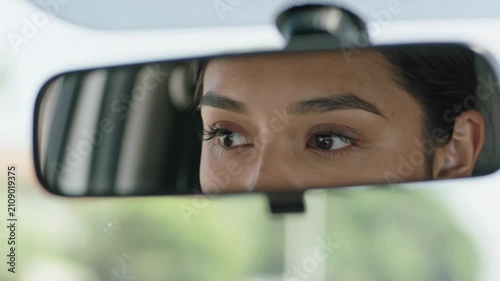 Close-up of woman's eyes reflected in car rearview mirror
