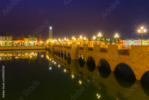 The Italian-style village is as beautiful as a painting at night, with reflections on the water and lights lined up along the walkways, creating a romantic atmosphere.