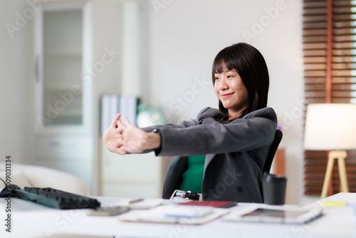 Fotografie Asian businesswoman stretching arms to relax and alleviate fatigue while working