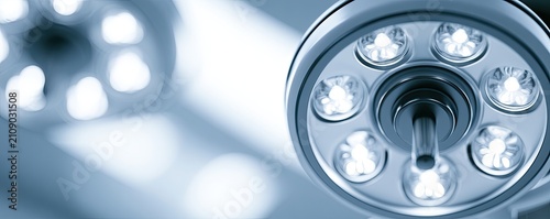 Close-up of a modern surgical operating room lamp with bright LED lights illuminating the scene.