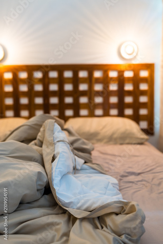 Foto Cozy and inviting unmade bed with soft cream and white linens and pillows with a