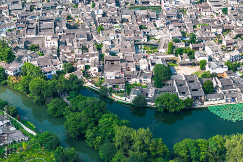Photos Aerial perspective of a historic traditional settlement with grey-tiled buildings adjacent to a winding green river and lush vegetation
