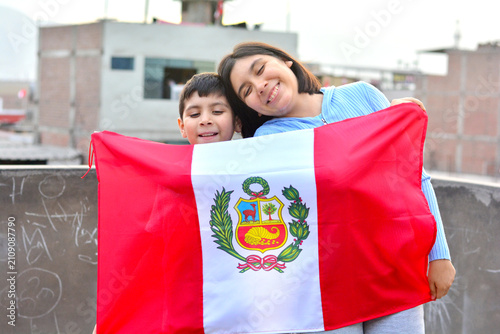 Two happy kids holding peruvian flag.