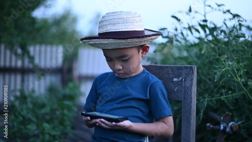 4 Year Old ASEAN Boy Using Tablet in Vegetable Garden Exploring Smart Farming AI Technology and Future Food Security Concept