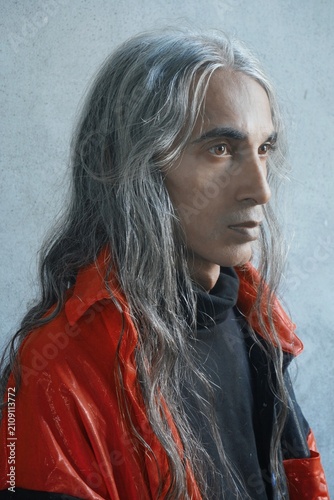 Side profile portrait of a stylish middle eastern man with long silver hair looking away thoughtfully