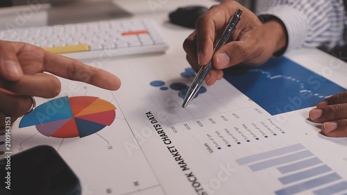 Two busy business men investors doing financial trading market data analysis. Male advisor and analyst consulting about stock exchange investing pointing at chart on laptop computer working in office.