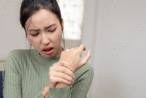 Foto Asian woman expressing pain holding aching hand suffering from wrist joint ache