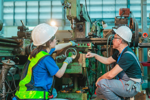 Senior Male Engineer Teaches Young Woman Technician to Operate Machinery in Industrial Factory