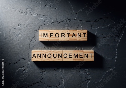 Important announcement text on wooden blocks on dark stone background